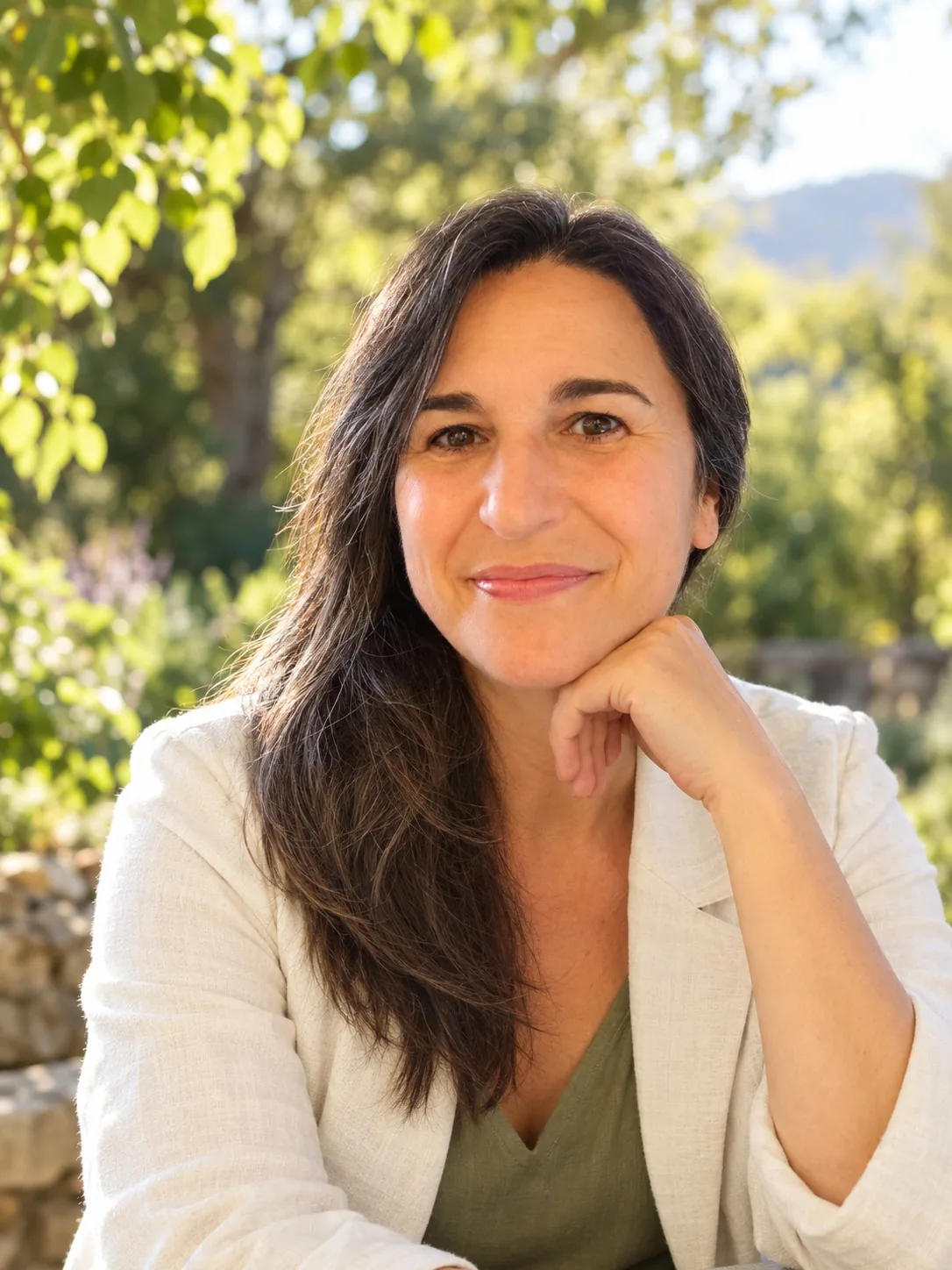 Ysabel Andréo souriante, le menton posé sur la main, dans le jardin du cabinet